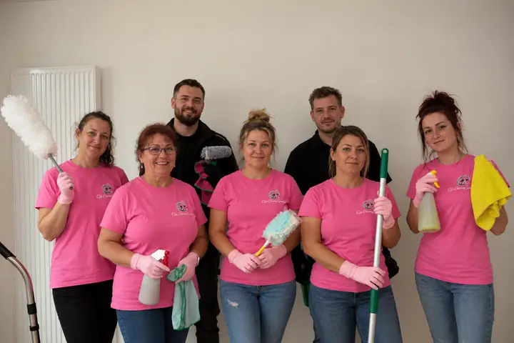 Het team van CS Cleaning Services in roze T-shirts met hun poetsmateriaal